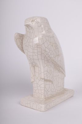 une statue de chouette blanche posée sur une table, à côté d'un vase