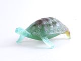une figurine de tortue en verre posée sur une surface blanche
