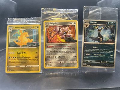 trois cartes Pokémon sont posées sur un sac en plastique