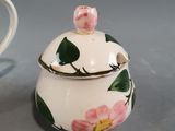 a white cup with a pink flower on it next to a white cup with a pink flower on it