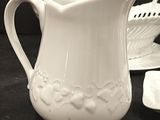 a white pitcher sitting on a table next to a plate