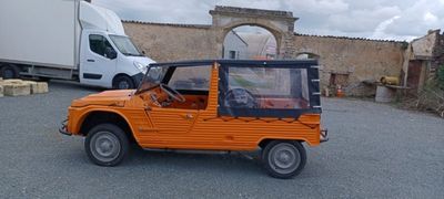 une jeep orange garée sur un parking, avec un camion en arrière-plan