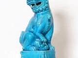 une statue bleue représentant un chien assis sur une boîte