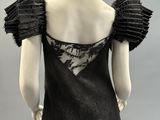 a black dress with ruffles and lace on the shoulders
