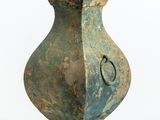 un vase vert muni d'une poignée en métal