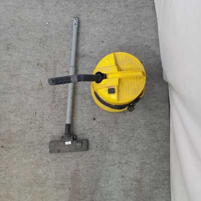 un aspirateur jaune et un seau jaune posés par terre