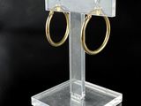a close up of a pair of gold hoop earrings on a clear stand