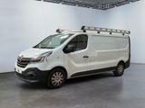La camionnette blanche est garée dans une grande pièce, avec une échelle sur le toit.