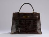 a brown crocodile skin handbag on a white surface