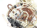 a pile of pearls and other jewelry on a white surface