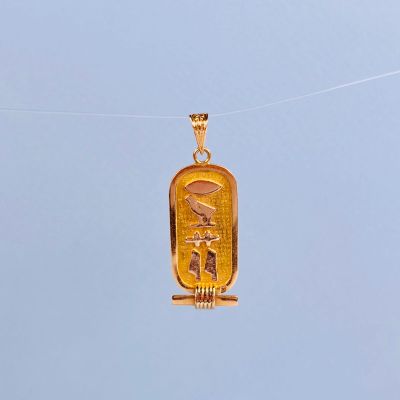 un pendentif en or au motif égyptien suspendu à une cordelette