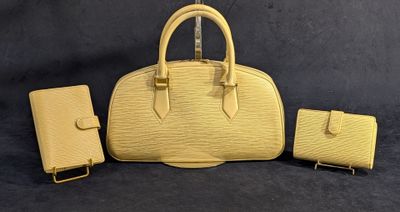 un sac à main jaune et un portefeuille posés sur un fond noir