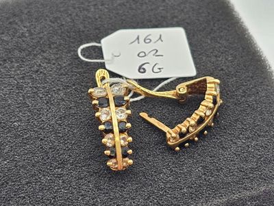 pair of gold tone earrings with clear stones on a black cloth
