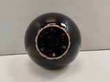 a black vase with a gold rim on a white surface