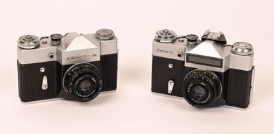 pair of black and silver cameras sitting on a white surface