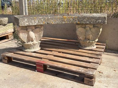 un banc en pierre posé sur une palette devant une clôture