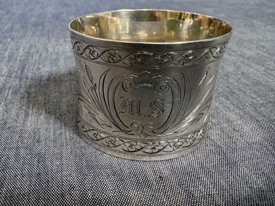une vieille coupe en argent portant un monogramme, posée sur un tissu bleu