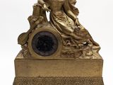 une horloge en or avec une femme assise dessus