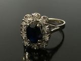 a close up of a blue sapphire and diamond ring on a black surface