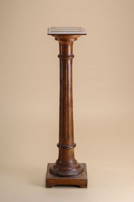 une image représentant un socle en bois surmonté d'un plateau en marbre, sur fond beige
