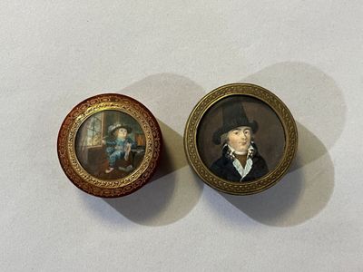 two miniature portraits of a man and a woman on a table