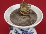 un vase bleu et blanc surmonté d'une pile de pièces de monnaie