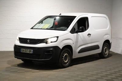 La petite camionnette blanche est garée dans une grande pièce.