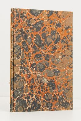 un livre aux motifs marbrés orange et noir posé sur une surface blanche