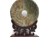 a green jade disk on a stand on a white background
