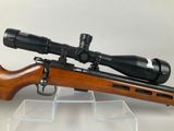 a close up of a rifle with a scope on a clear stand