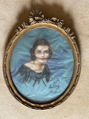 an old picture of a woman in a blue dress is hanging on a wall
