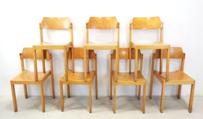 six wooden chairs that are lined up against a white wall