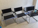 three chairs in a waiting room with a painting on the wall