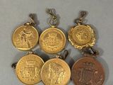 four gold medals are shown on a white surface