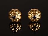 une paire de boucles d'oreilles en or ornées de saphirs sur un fond noir