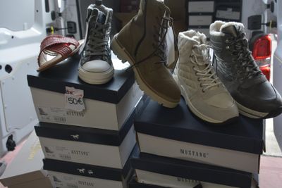 several pairs of shoes are stacked on top of boxes in a room