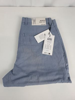 un gros plan sur un pantalon bleu posé sur une surface blanche