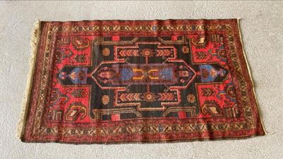 Le tapis posé au sol est rouge et noir et comporte un motif.
