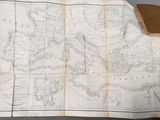 an old map of the world on a table with a book on it