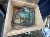 une boîte contenant une perceuse et une cordelette