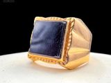 bague en or jaune avec une pierre noire au centre sur un fond blanc