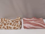 two towels are sitting on a white table with a brown and white animal print blanket