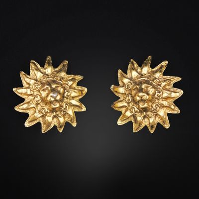 a pair of gold plated sunflower earrings on a black background