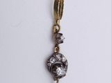 a close up of a gold and diamond pendant on a white surface