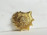 a close up of a gold brooch on a white surface