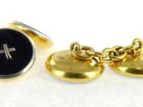 two gold tone cufflinks with a cross and a black button