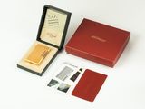 a red box with a gold lighter and a card in it