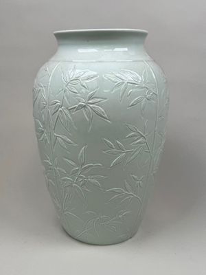 un grand vase vert orné de feuilles de bambou