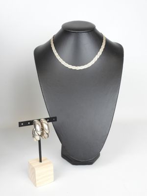 black mannequin with a white rope necklace and a wooden stand