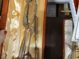 a woman holding a box with a set of silverware in it